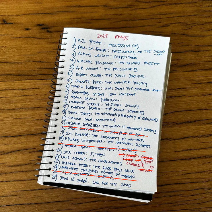A list of books is written on a notebook page. Some are crossed out. 